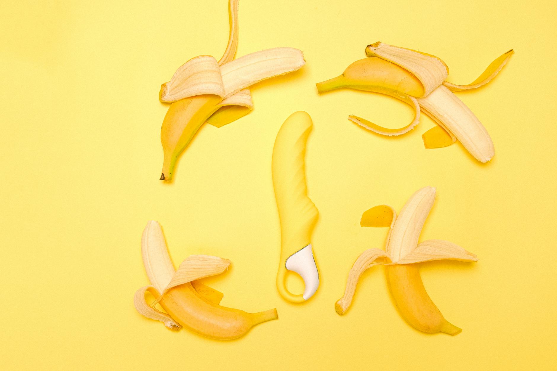Yellow Lemon clitoral vibrator on a bright yellow background with fresh fruit