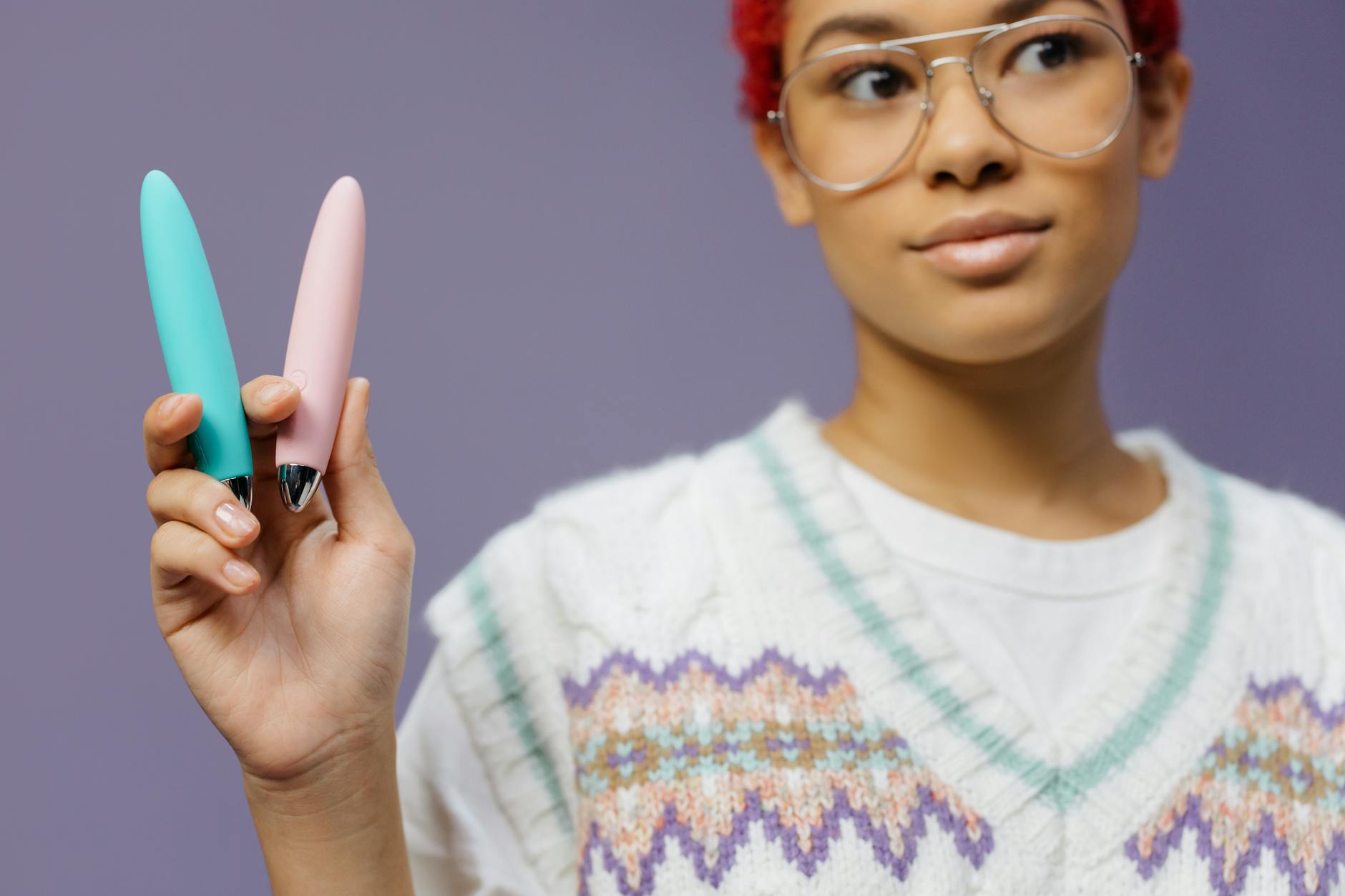 Woman holding a colorful vibrator against a purple background, representing intimate pleasure and partnership.