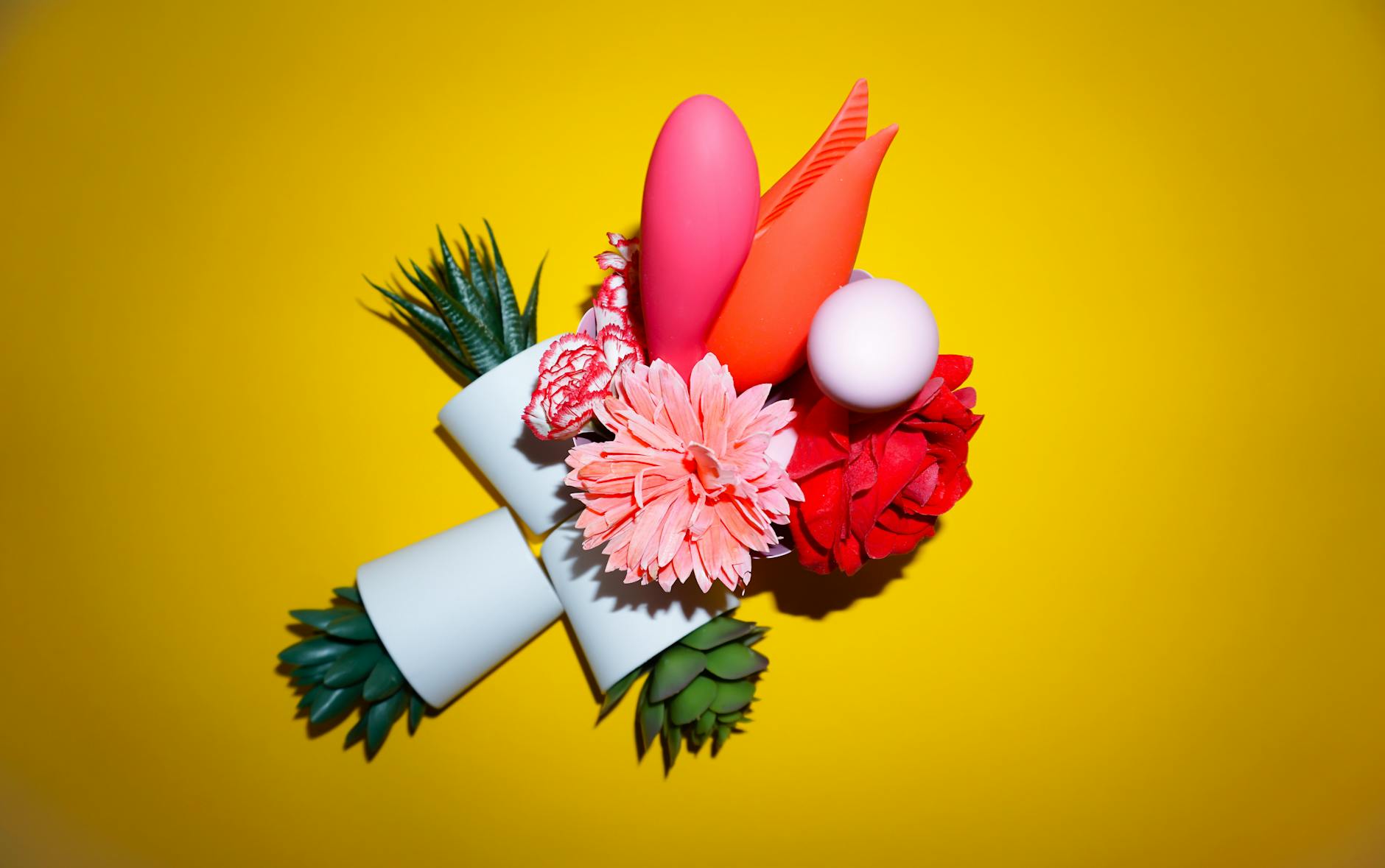 A yellow silicone vibrator surrounded by peeled bananas on a yellow background